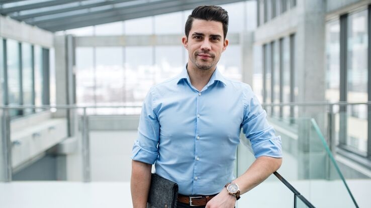 Ein junger Geschäftsmann steht im Flur vor seinem Büro.